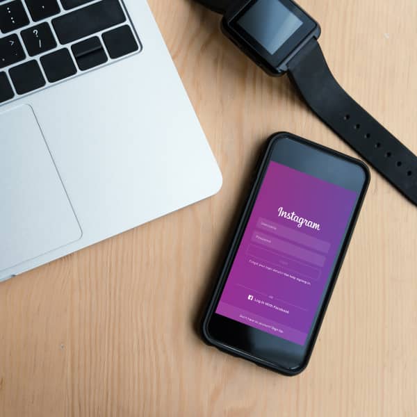 Téléphone ouvert sur Instagram avec une montre et un laptop sur un bureau